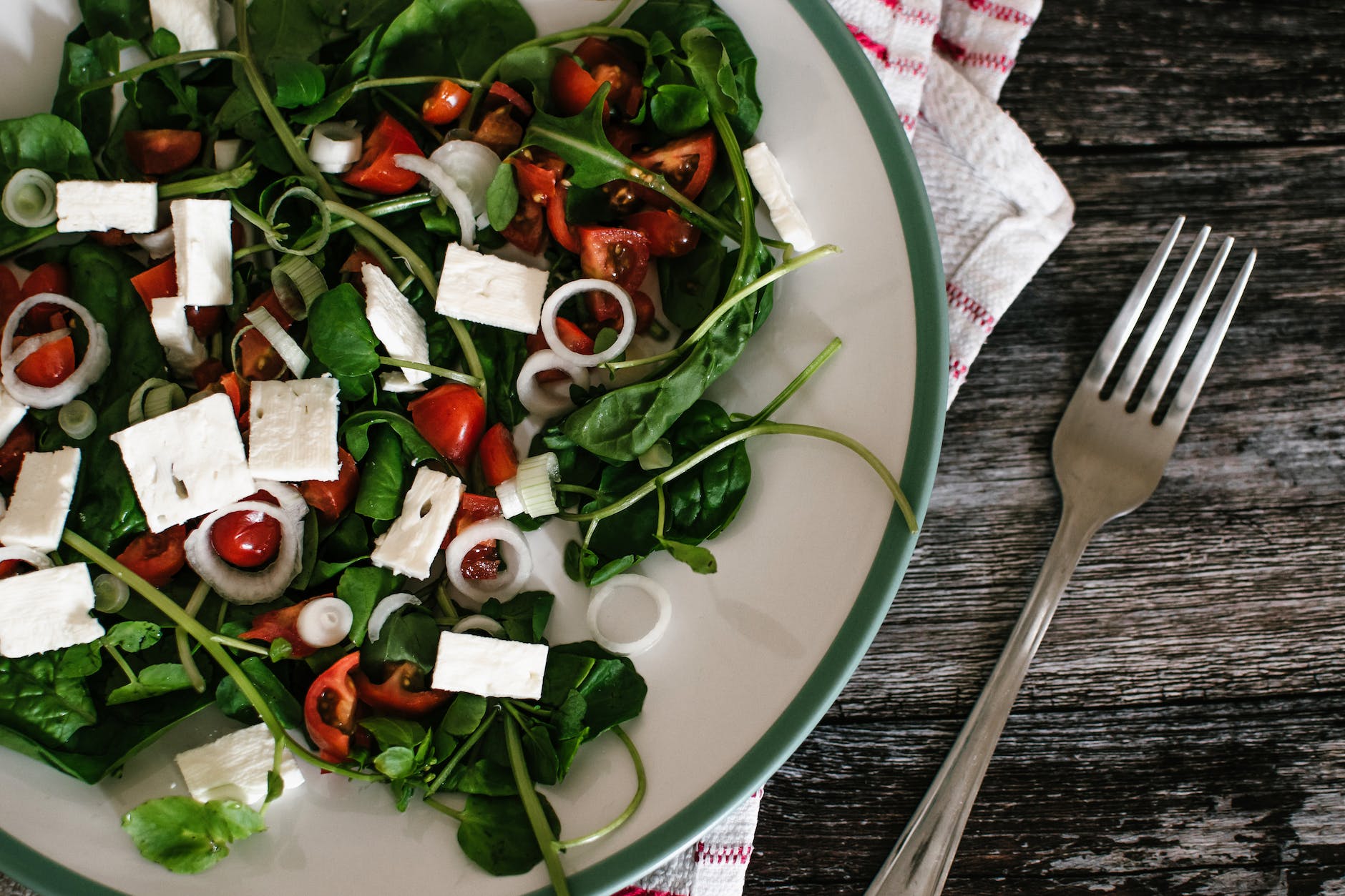 vegetable salad on white ceramic plate beside grey stainless steel fork